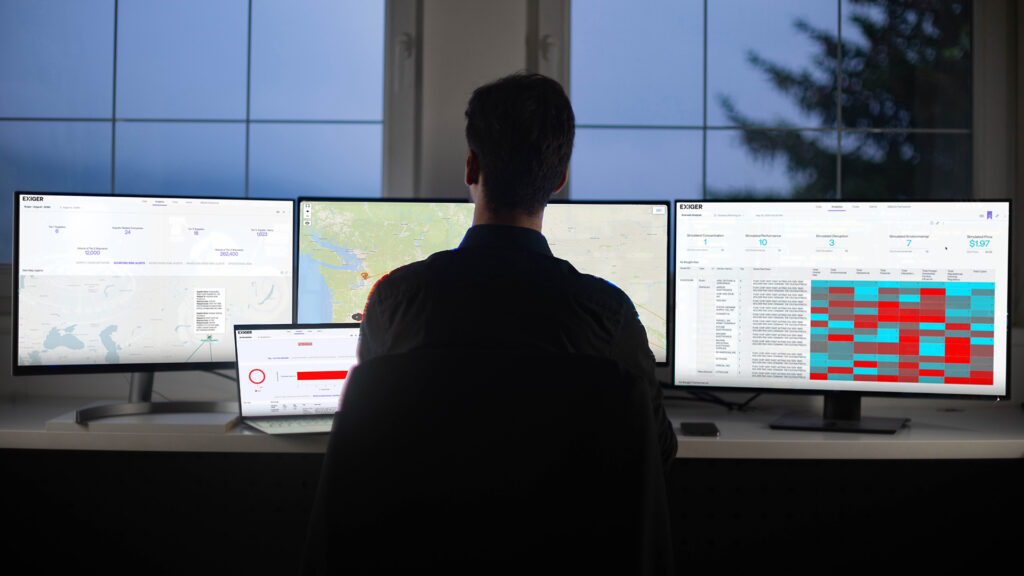 Analyst using 1Exiger platform across multiple screens, monitoring global supply chain risk maps, data visualizations, and performance dashboards.